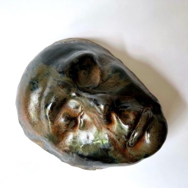 Ceramic sculpture of a face glazed with metallic finish