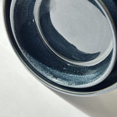 Nested stoneware bowls in a midnight blue glaze on a white background